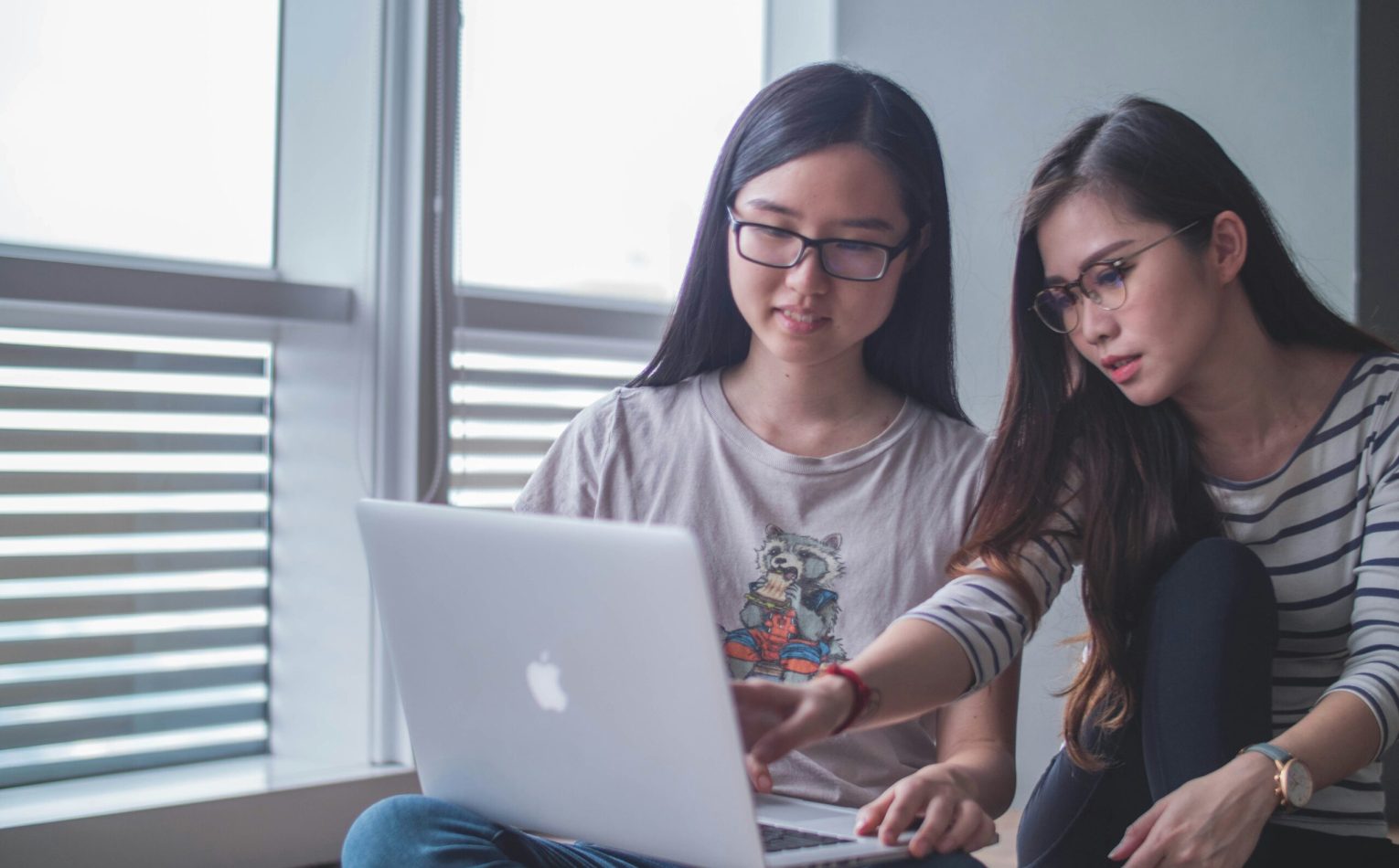 Two young women sitting together and ready a Flywayy blog post on cabin crew